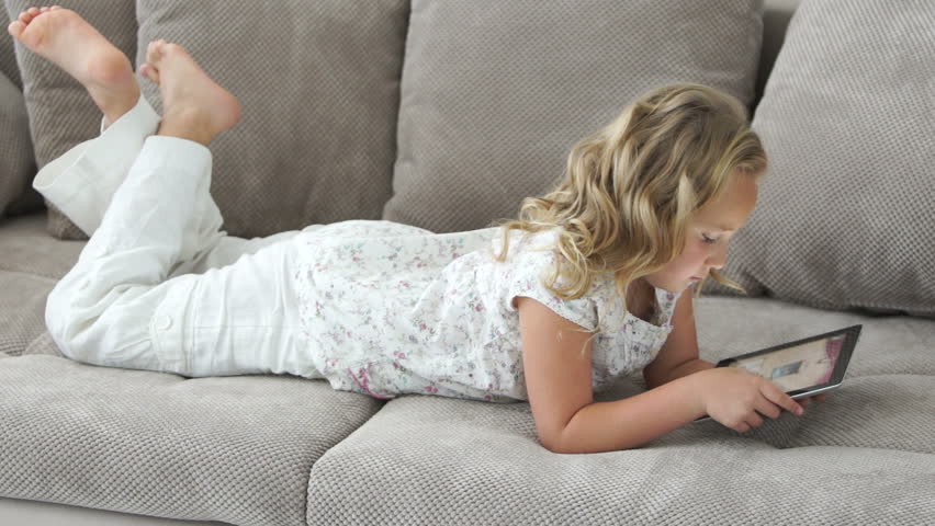 Cute girl with tablet pc lies on the couch
