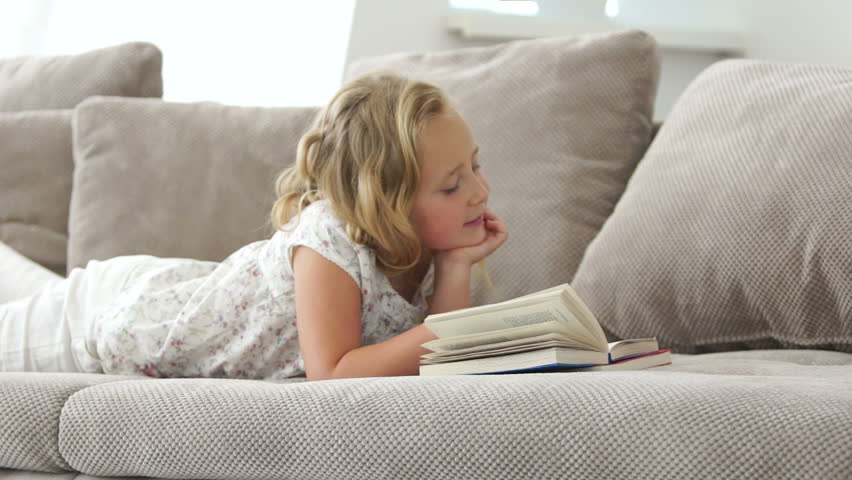 Child reading the book and lying on the sofa

