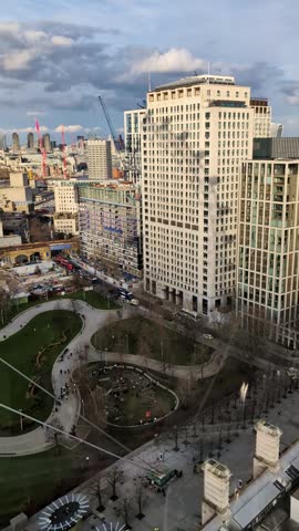 Aerial perspective capturing the dynamic urban landscape of London, England, with contemporary skyscrapers overlooking a bustling city park where people enjoy their leisure time