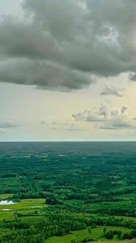 Dark clouds drift over a wooded area under a grey sky. Hyperlapse shot.