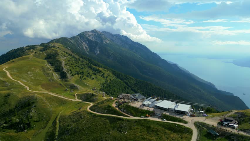 Aerial view gliding along Monte Baldo mountain ridge with cable car station visible