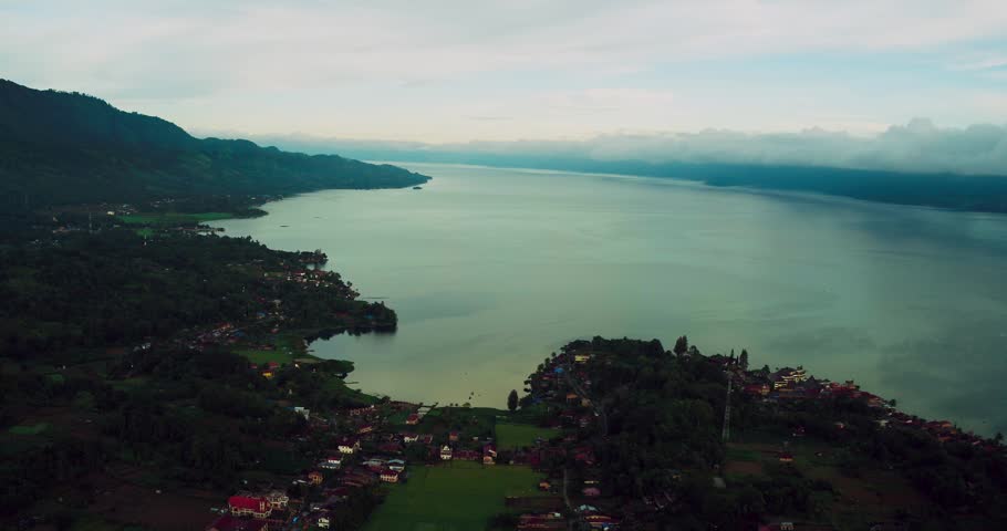 Aerial flyover capturing lush green forest hills surrounding Lake Toba.