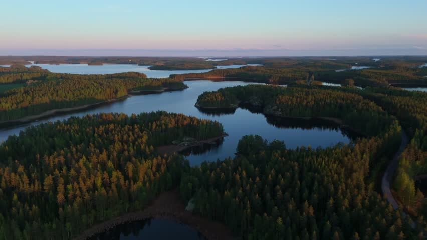 Lake Saimaa near Puumala, Finland aerial forward flight above forested islands and winding waterways under warm evening light, showcasing Nordic wilderness and archipelago scenery.