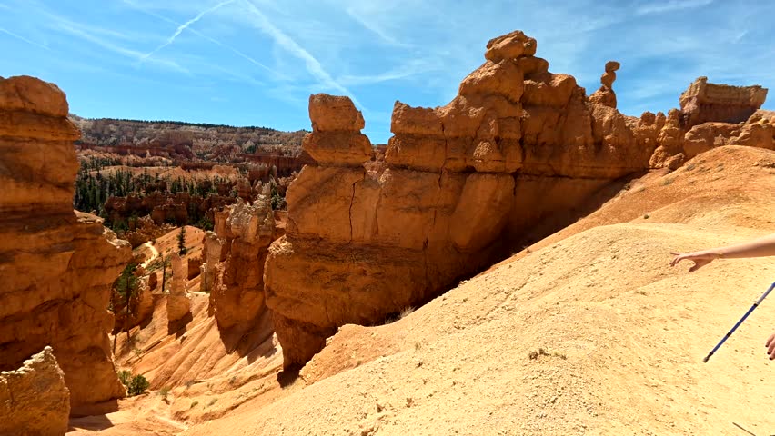 Stunning view panning down the navajo loop hiking trail in bryce canyon national park, revealing the famous orange hoodoos and natural amphitheater under a beautiful blue sky in utah, usa