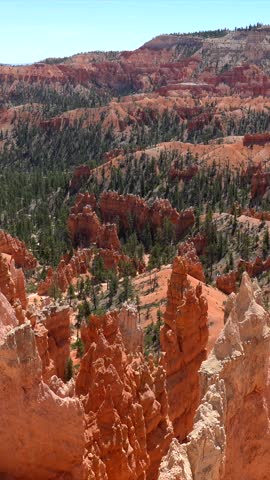 Amazing panoramic view of the bryce canyon amphitheater in utah, featuring stunning red rock hoodoos, unique geological formations, and green pine trees under a clear blue summer sky