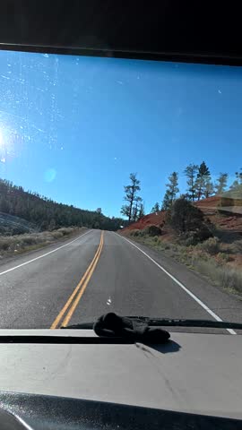 Point of view shot driving a car on a winding asphalt road through the stunning landscape of bryce canyon national park in utah on a beautiful sunny day with a clear blue sky