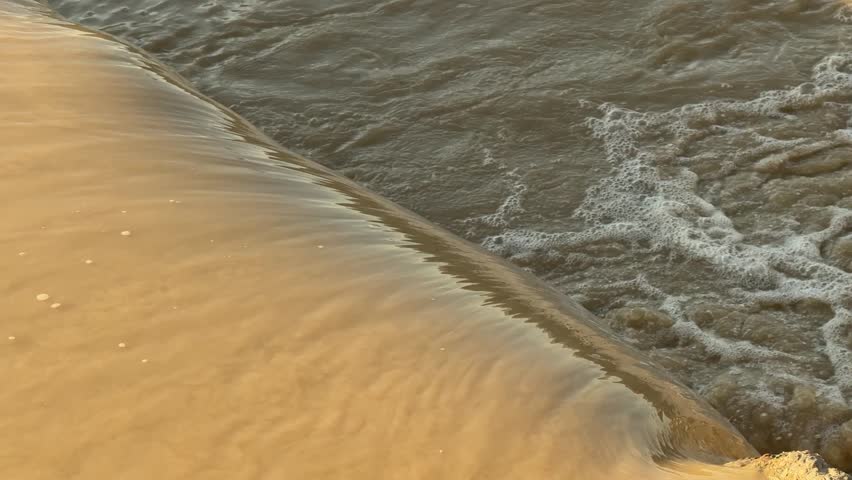 Golden sunset light reflecting on water flowing over dam edge.