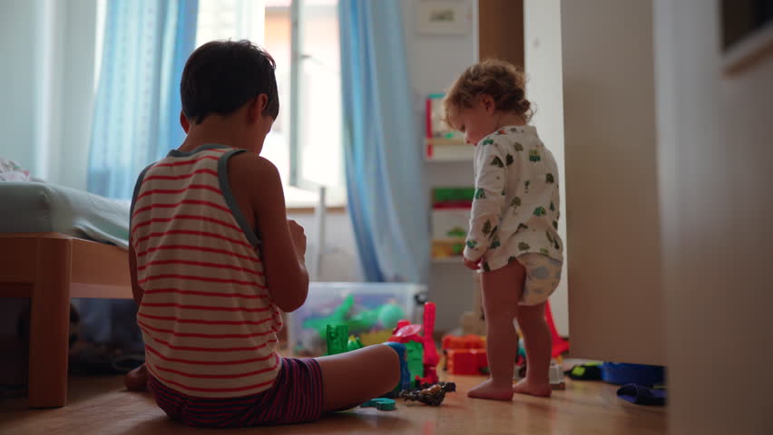 Two children engaged with toys on floor in relaxed indoor setting, interacting quietly and sharing space, representing creativity, development, bonding and authentic family life