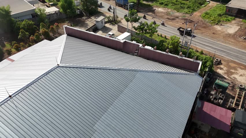 A view from the corrugated metal roof of an industrial warehouse building along the roadside.