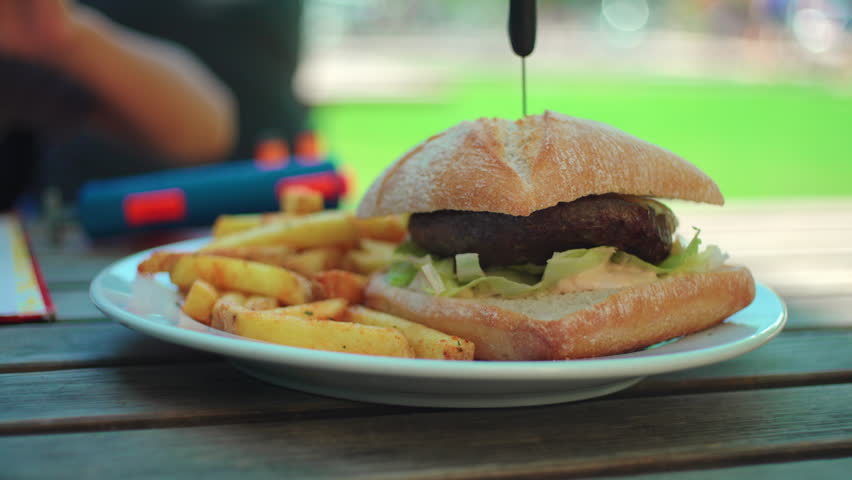 Fresh burger and crispy fries plated at open air restaurant highlighting indulgent meal choice, recreation and relaxed daytime dining experience