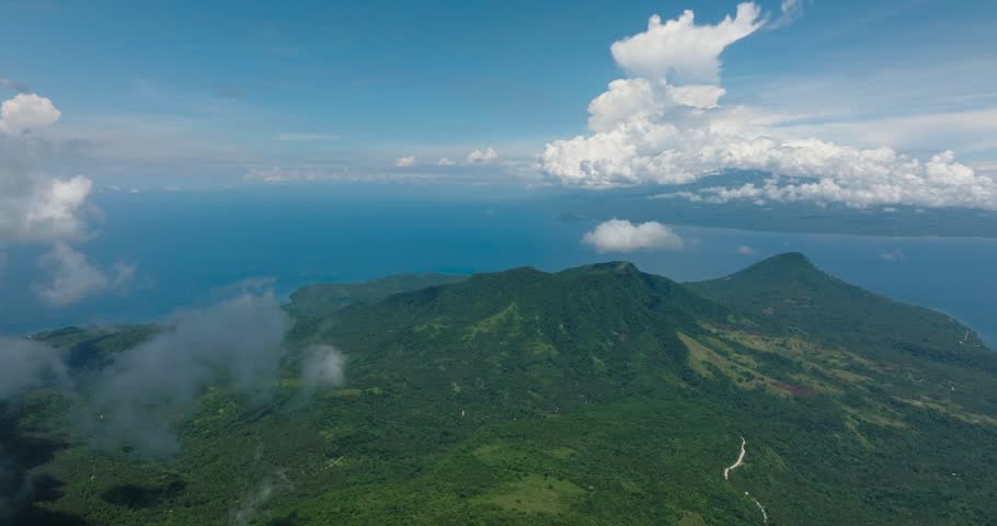 Top view of mountain with lush green forest in Camiguin Island. Blue sky and clouds. Philippines.