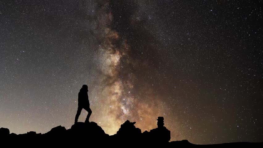 Silhouettes of hiker against the backdrop of the bright Milky Way galaxy.