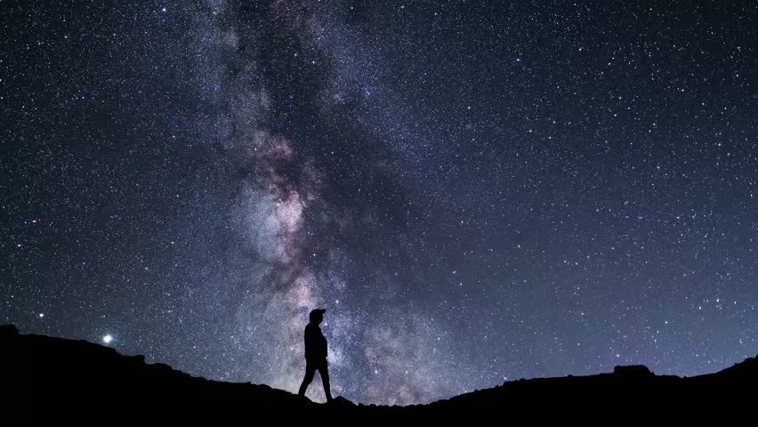 Silhouettes of hiker against the backdrop of the bright Milky Way galaxy.