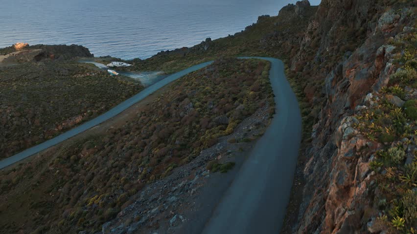 Sunrise scenery on the coastline of Island Crete with winding road through the high mountains, drone aerial view