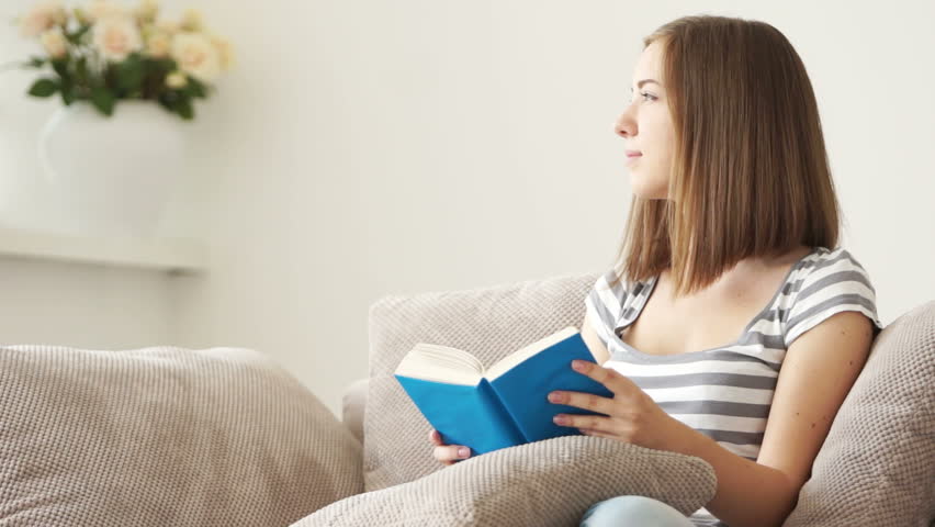 Girl sitting on sofa and reading book
