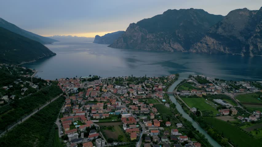 Aerial view of lakeside town near mountains at dusk with river and rooftops visible