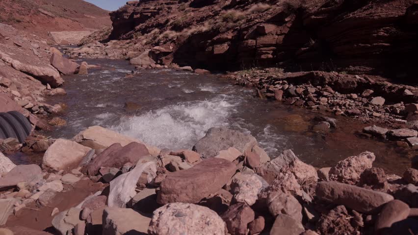 Stream rushing over rocks through narrow rocky canyon with splashing turbulent water