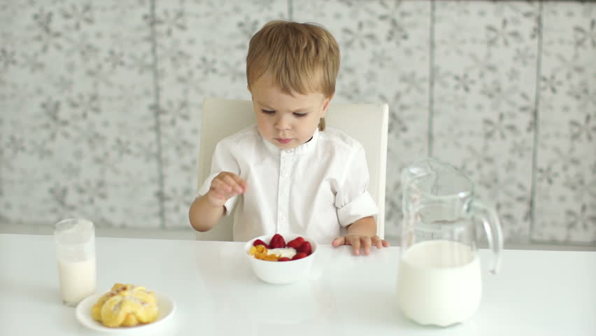 Boy eating fruit from the bowl by hand
