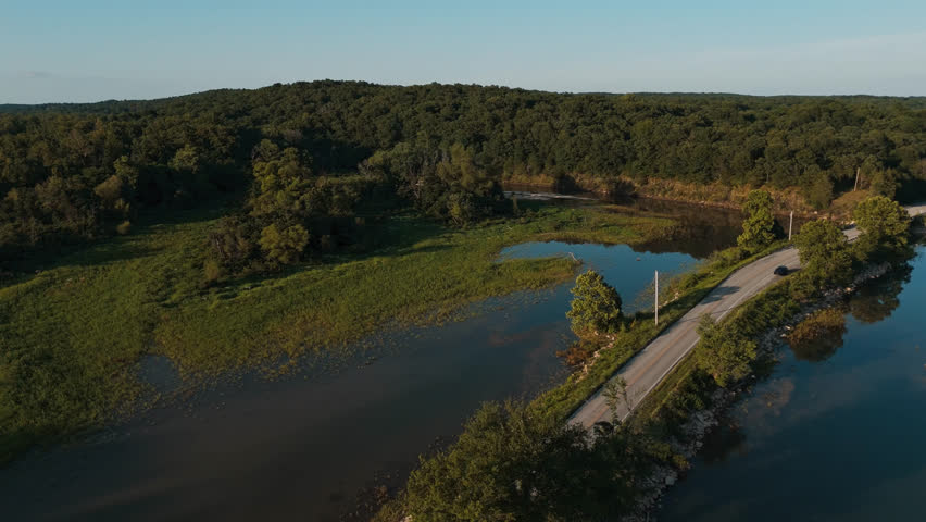 Flooded Bush Creek Bay wetlands and rural road beside Lake Eucha forest landscape, drone overview