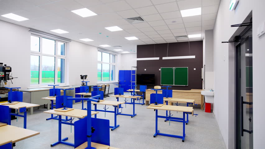 Bright workshop room contains blue workbenches and green chalkboard. Contemporary educational space ready for technical lessons