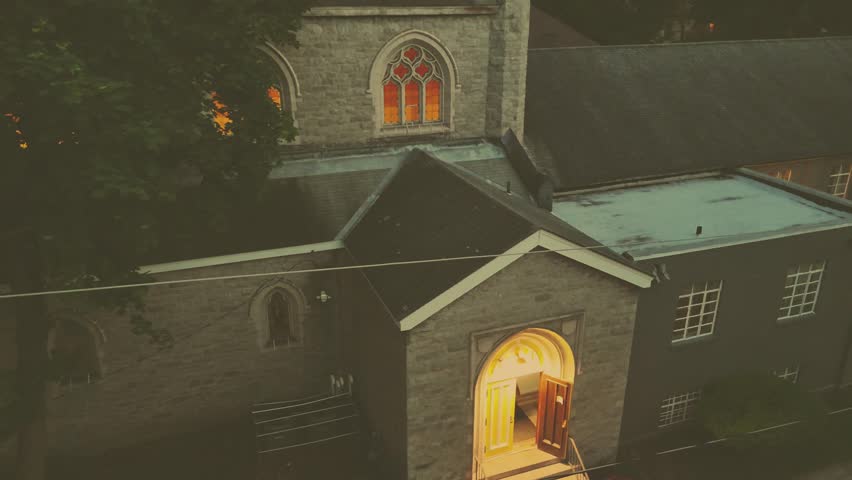 The backside of a church as the windows glow with warmth.