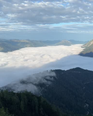 Beautiful view from the Austrian Alps. Above the clouds as they move across the valley under a cloudy blue sky, lovely summer scenery. Perfect for summer, nature, mountain, geology, travel concepts
