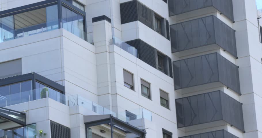 Detailed view of a contemporary residential building facade with glass balconies and geometric architectural lines in Madrid, Spain