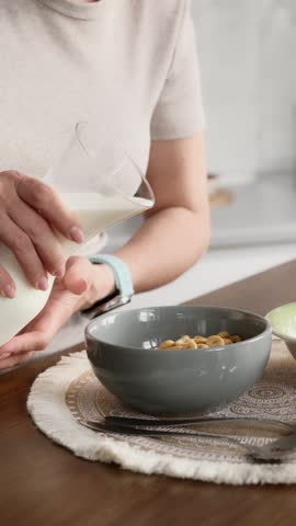 Close-Up Vertical Video Of A Woman Pouring Milk Into Cereal