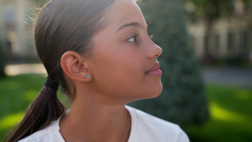 Close up American Latina happy little girl outdoors smiling looking at camera portrait child school student pupil teenage in city college academy primary education face kid schoolgirl daughter study