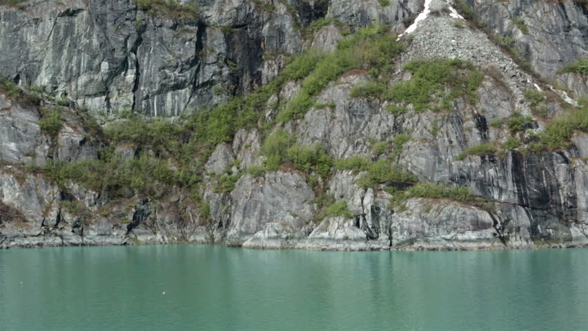 Alaska inside passage mountain coastal ocean. Shore along Alaskan Pacific and Glacier Bay. Steep mountains drop into deep fjords carved by ancient ice flows and glaciers. Scenic landscape water.