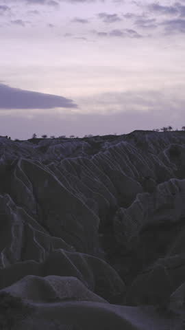 Purple evening sky over dark rocky hills and rugged natural formations.