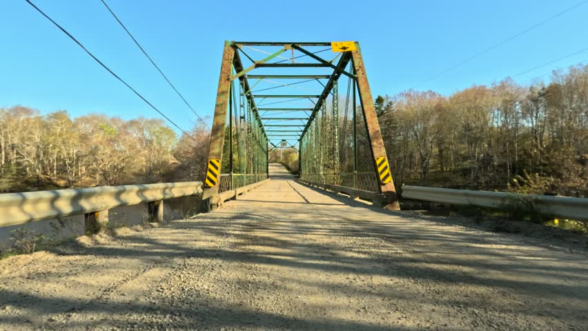 Beautiful old green iron truss bridge over a river on a rural dirt road, Nova Scotia, Canada.
