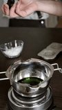 Close up of a person using a digital kitchen thermometer to check the temperature of green melted wax in a stainless steel pot. Professional candle making process at home. Vertical shot - Powered by Shutterstock - Get 15% off with code: PIKWIZARD15