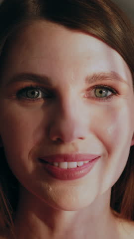 Close-up of a woman s face with green eyes and a gentle smile, showing subtle expressions and skin texture. The calm detail conveys beauty, nuance and the delicate rhythm of human emotion