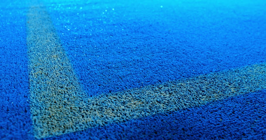 Extreme super slow motion close-up of a tennis or padel ball bouncing near the court line. Detailed blue surface texture captured at 1000fps with dynamic sports action in macro detail.