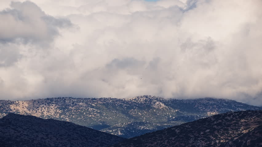 Dark storm clouds over mountains and coastline landscape.
