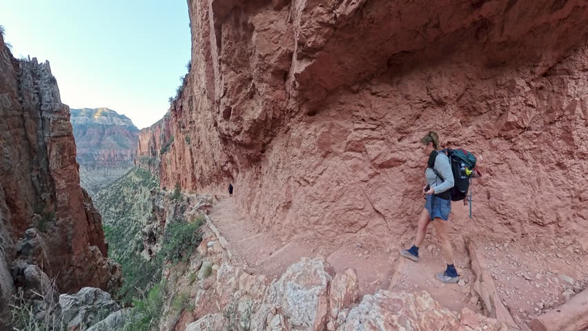 Side View of Couple Hiking Along Cliff of Canyon along the North Kaibab Trail