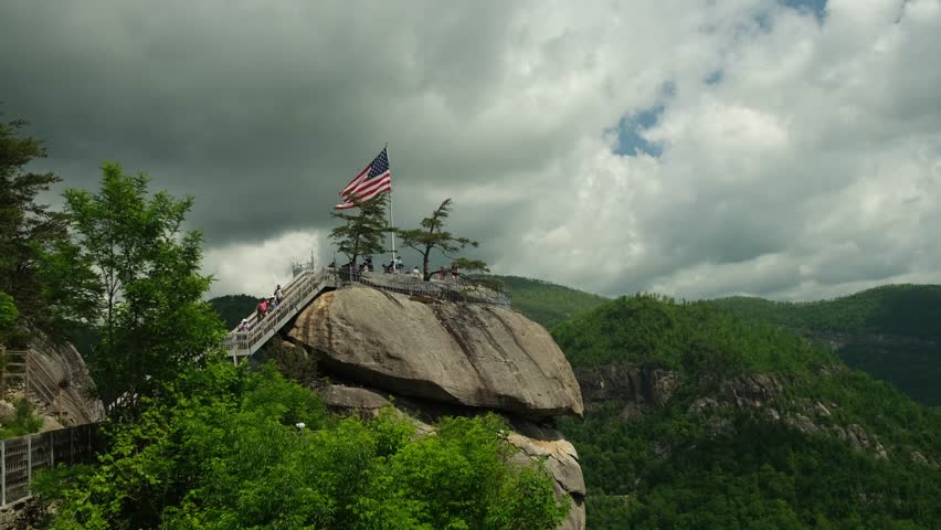 Flag on top of large rock formation in scenic area with clear blue sky