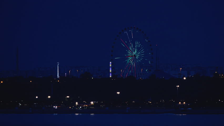 Fireworks exploding in the night sky over a distant city.