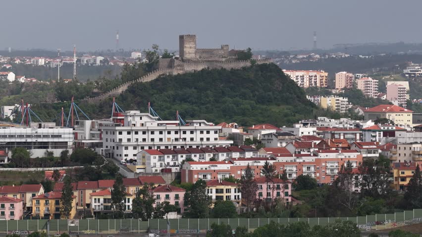 Aerial view of the medieval Castelo de Leiria perched on a green hill overlooking the city rooftops and urban landscape in Leiria, Leiria, Portugal.