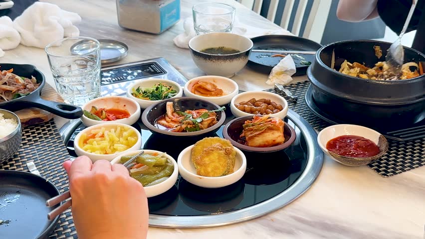 High angle shot of people eating traditional Korean side dishes and bibimbap in a restaurant