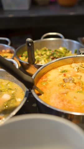 Close-up shot of bubbling red curry soup in a metal pot at a Bangkok market