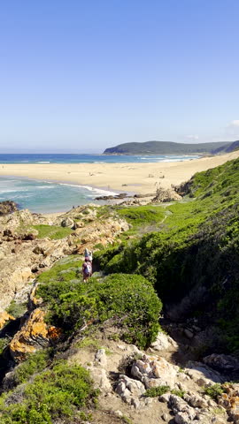 Hikers on Robberg hiking trail going toward beach at The Island. Vertical