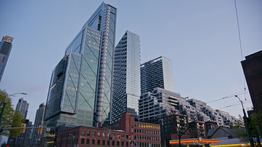 Glass facade skyscraper architecture in downtown Toronto with light trails from urban traffic flowing, modern city business district and residential buildings