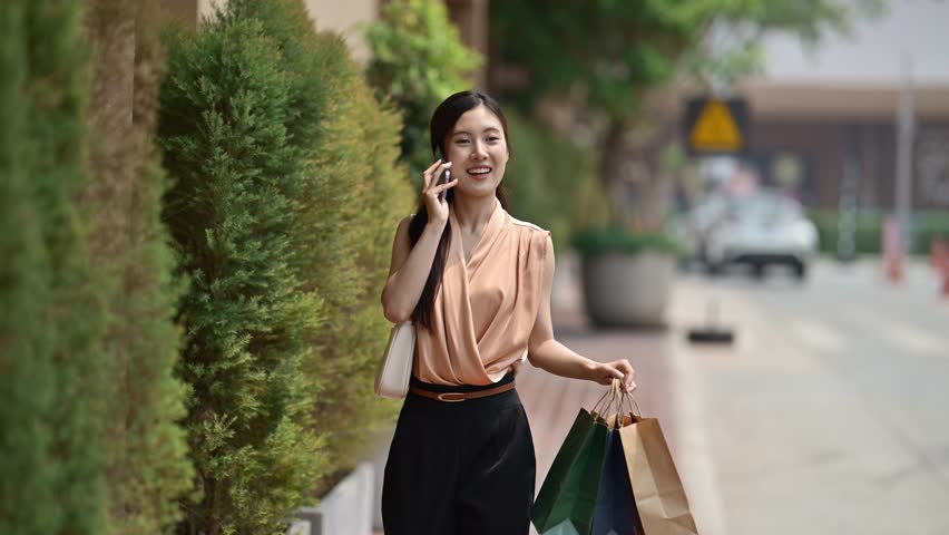 Young Woman Shopping with Bags and Talking on Phone Outdoors