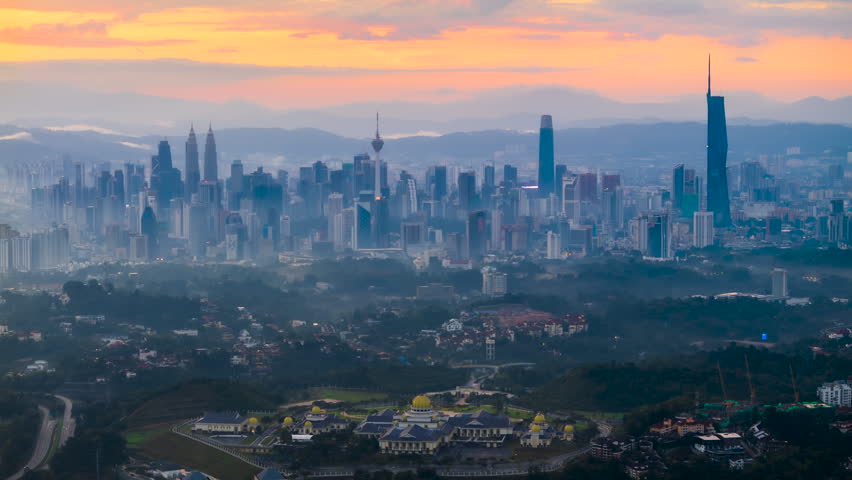 Cinematic transition of a misty dawn breaking over Kuala Lumpur, Malaysia, a Southeast Asian metropolis. Golden hour sunlight hitting urban architecture, perfect for themes of growth, new beginnings, business development, and global travel.