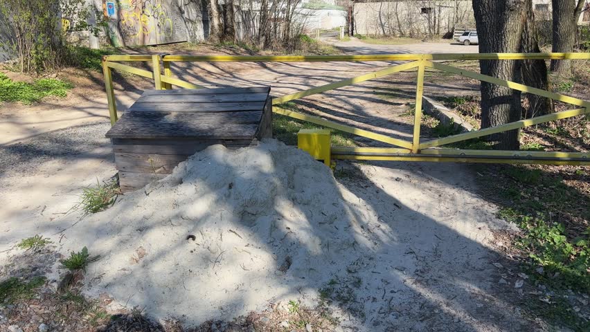 Automatic sliding univalve entrance gates made of metal frame painted in yellow and installed on a dirt road, view during closing

