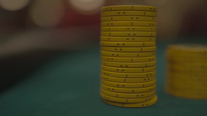 Slow motion close-up of columns of yellow poker chips being removed, casino