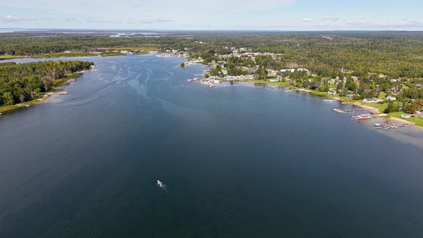 Aerial view of a tranquil lake and shoreline with boats and natural beauty in Hessel, Michigan.