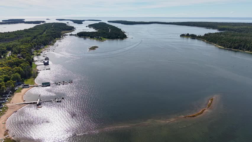 Aerial view of a tranquil lake in Hessel, Michigan with lush wilderness surrounding the shoreline and islands scattered throughout.